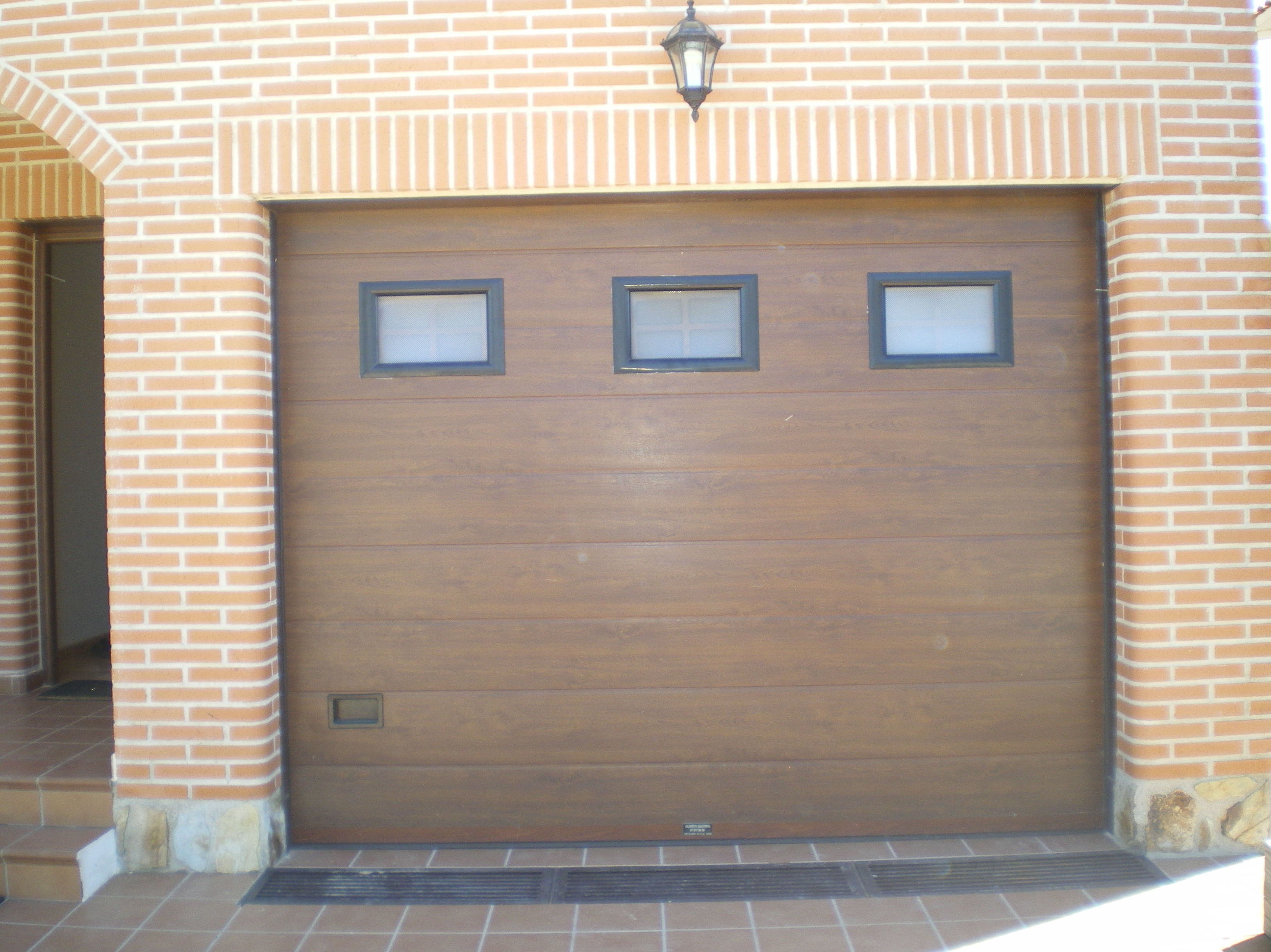 Puerta seccional color madera, con ventanas.