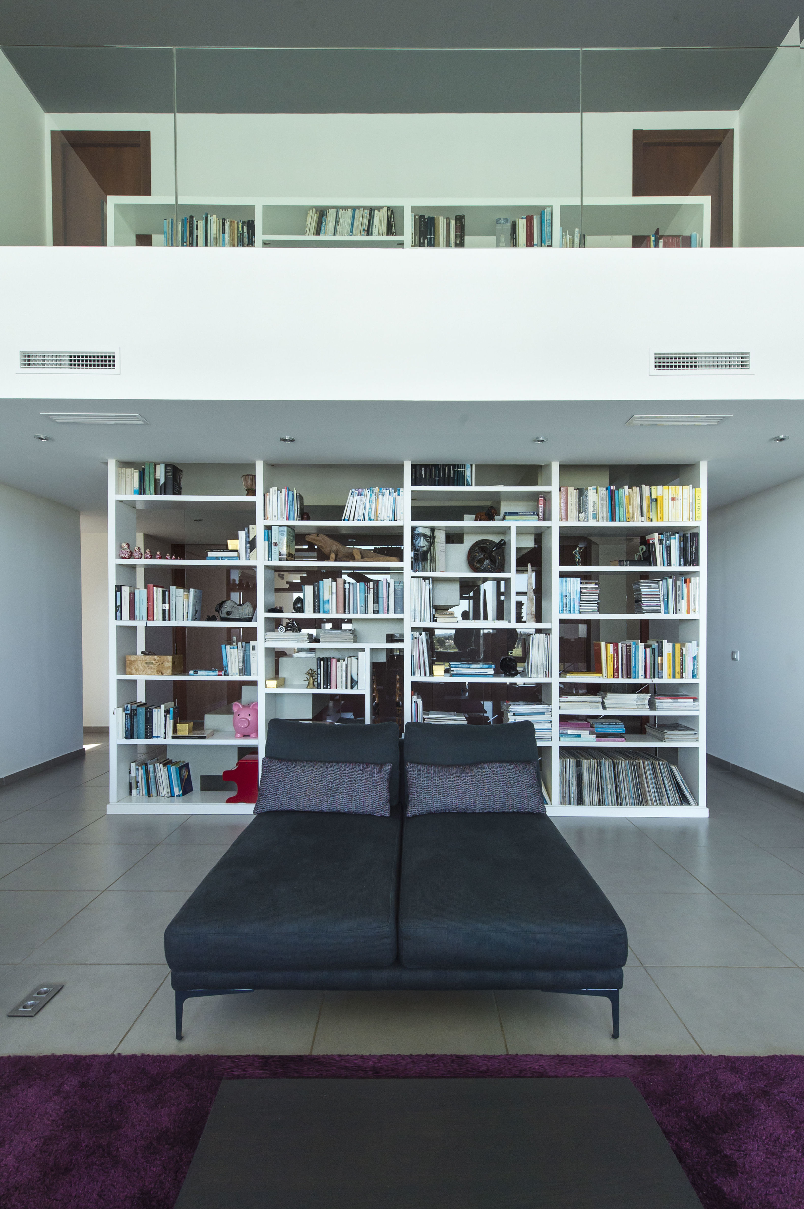 Salón a doble altura. La librería acompaña desde el arranque de la escalera. Fotos: http://studio3creativos.es
