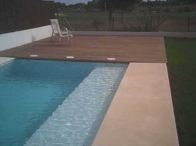 Piscina lineal revestida de gresite y el borde con piedra natural. Solarium con pavimento de Teka. Piscina lineal revestida de gresite y el borde con piedra natural. Solarium con pavimento de Teka.