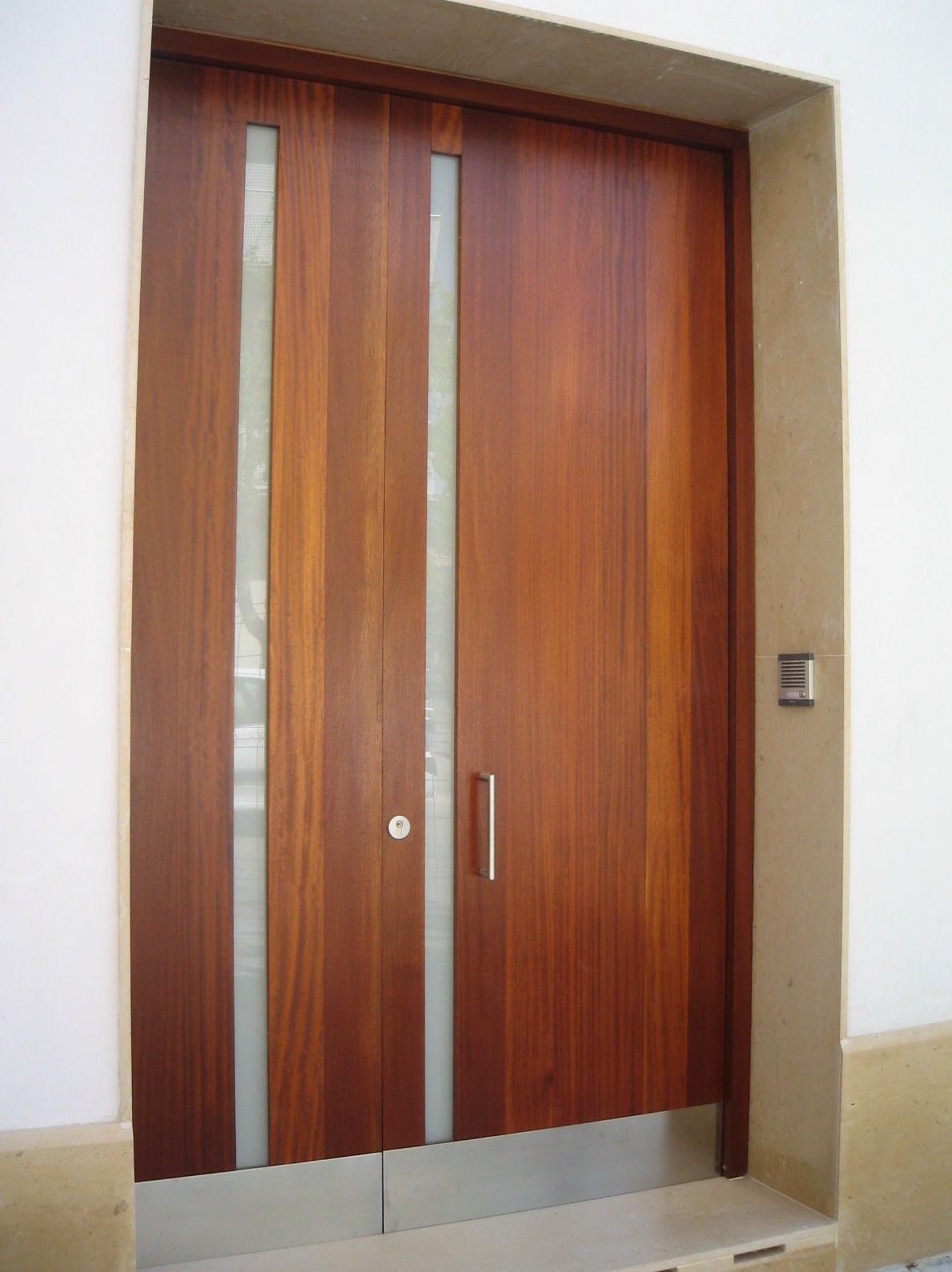Puerta en madera de Iroko, con zócalo inferior para protección en inox. Puerta en madera de Iroko, con zócalo inferior para protección en inox.