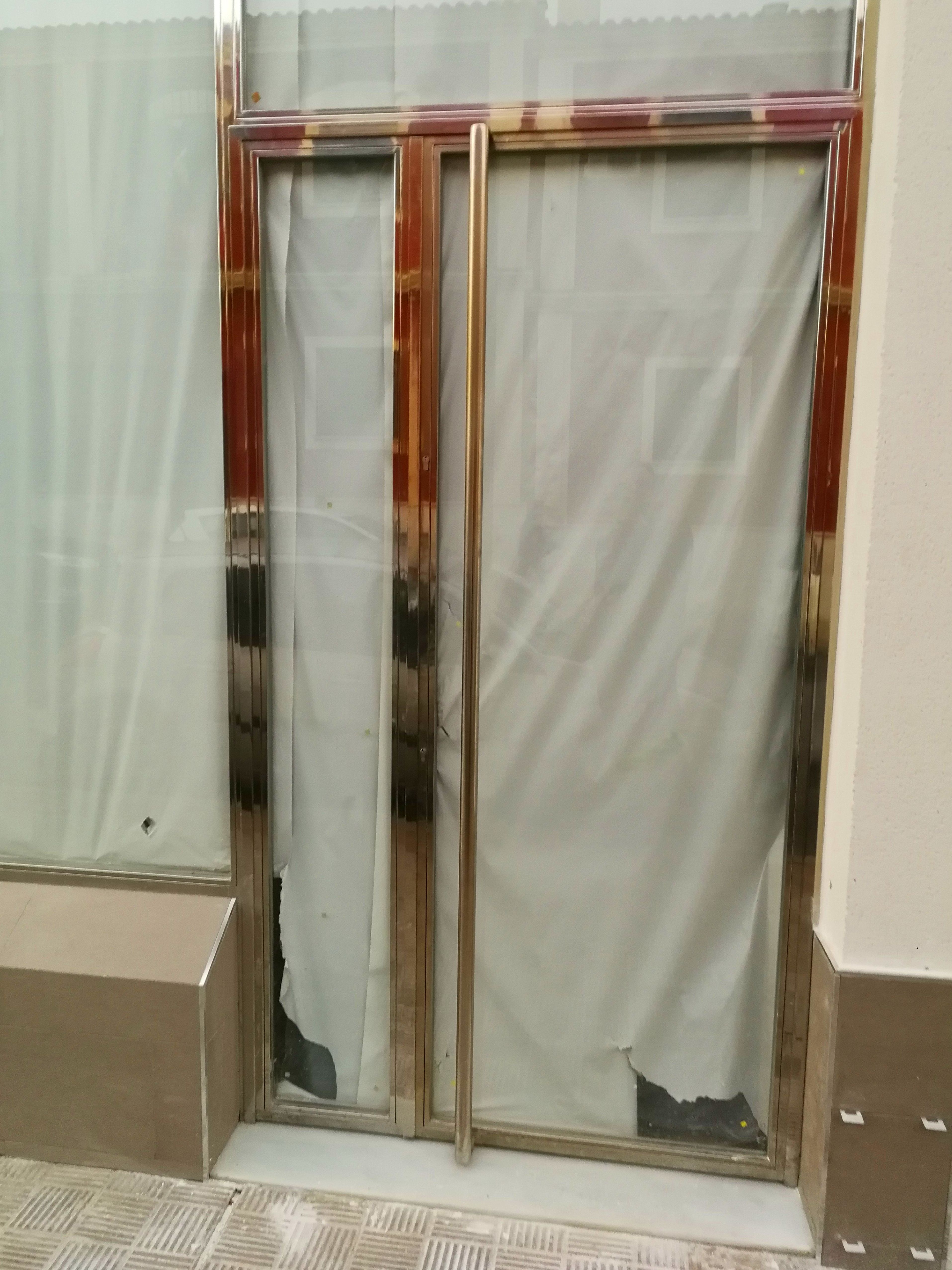 Puerta y escaparate de acero inoxidable y vidrio diseñada y fabricada a medida para local comercial Puerta y escaparate de acero inoxidable y vidrio diseñada y fabricada a medida para local comercial