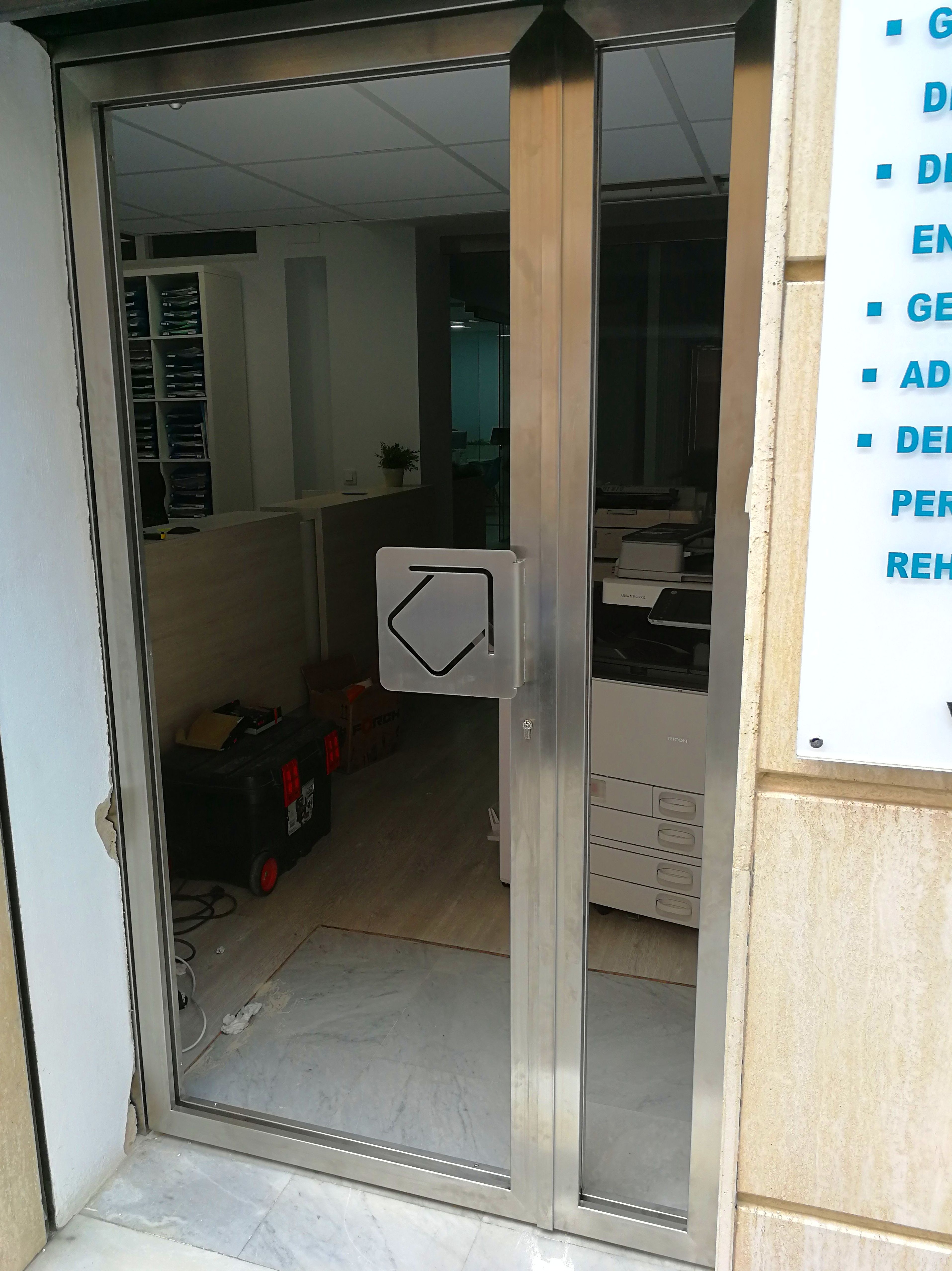 Puerta de acero inoxidable y vidrio con tirador de acero inoxidable personalizado con el logo de la empresa Puerta de acero inoxidable y vidrio con tirador de acero inoxidable personalizado con el logo de la empresa
