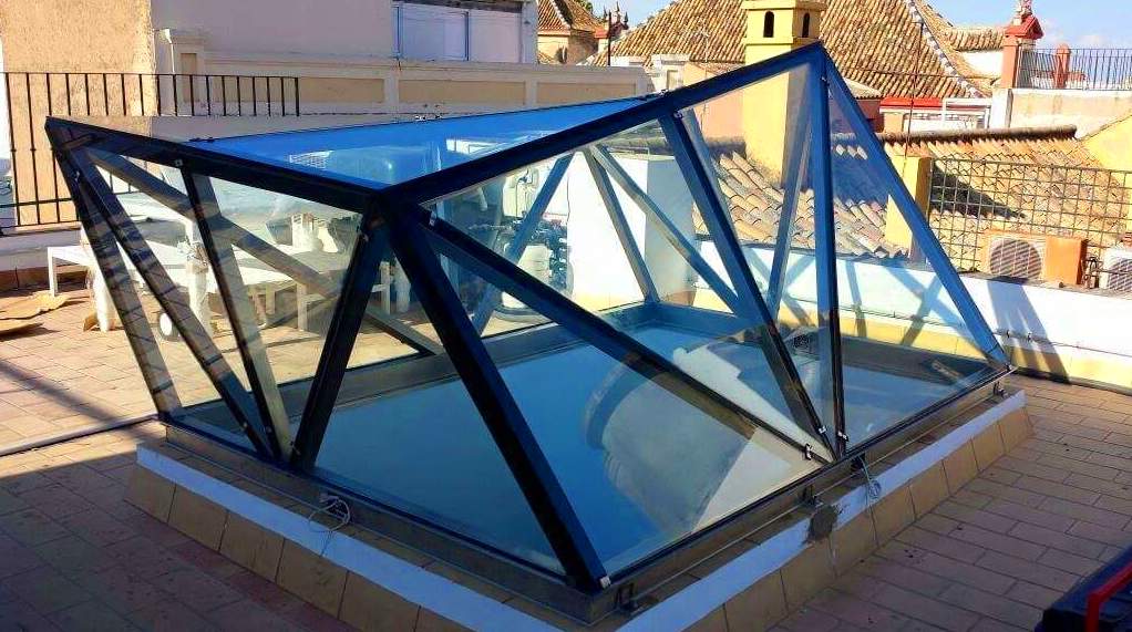 Montera de diseño de acero inoxidable y vidrio montada como punto de luz para patio interior. Montera de diseño de acero inoxidable y vidrio montada como punto de luz para patio interior.