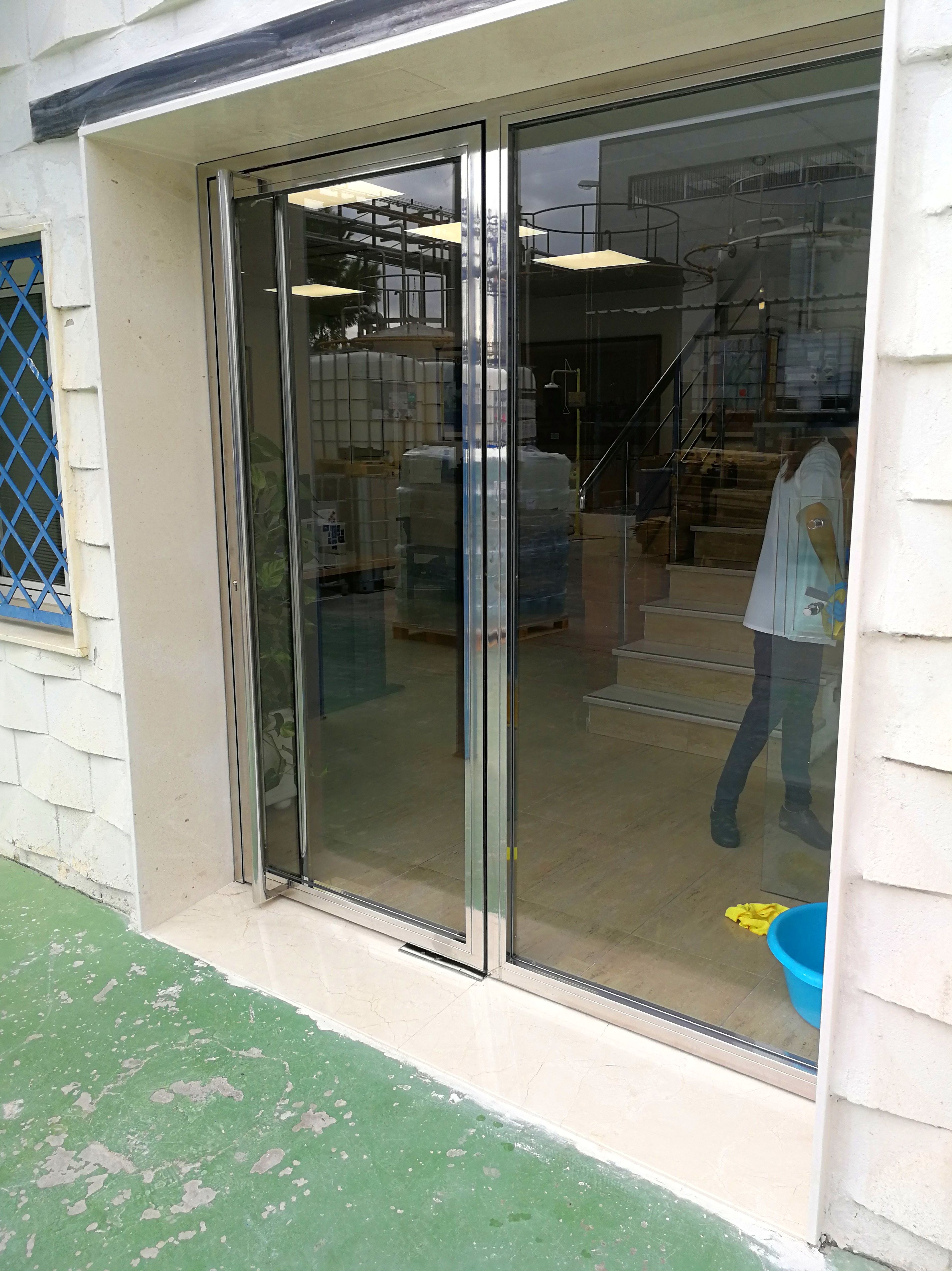 Puerta de acero inoxidable y vidrio diseñada y fabricada a medida para edificio empresarial de zona industrial. Puerta de acero inoxidable y vidrio diseñada y fabricada a medida para edificio empresarial de zona industrial.