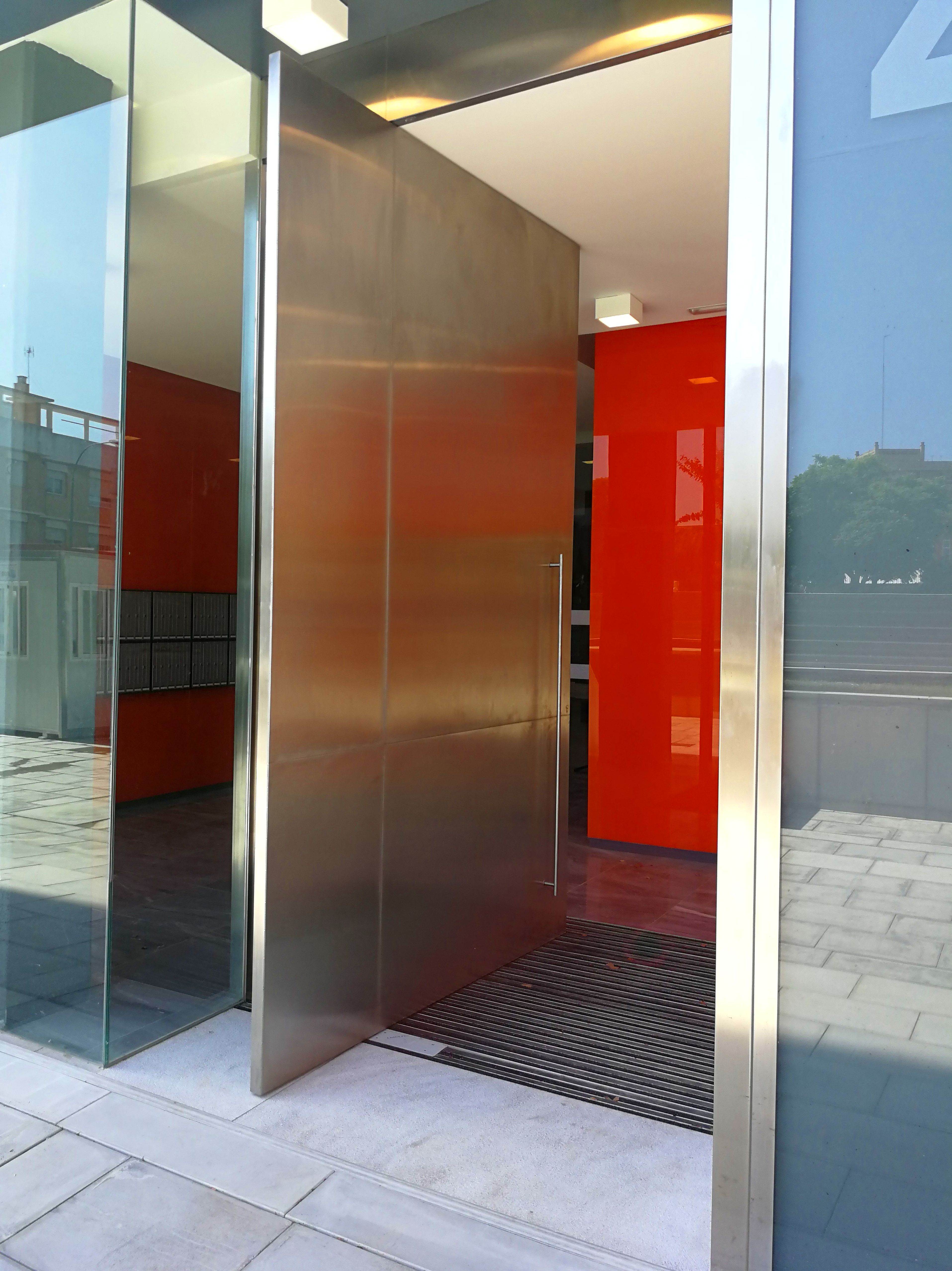 Puerta de acero inoxidable con diseño personalizado para edificio de comunidad de vecinos. Puerta de acero inoxidable con diseño personalizado para edificio de comunidad de vecinos.