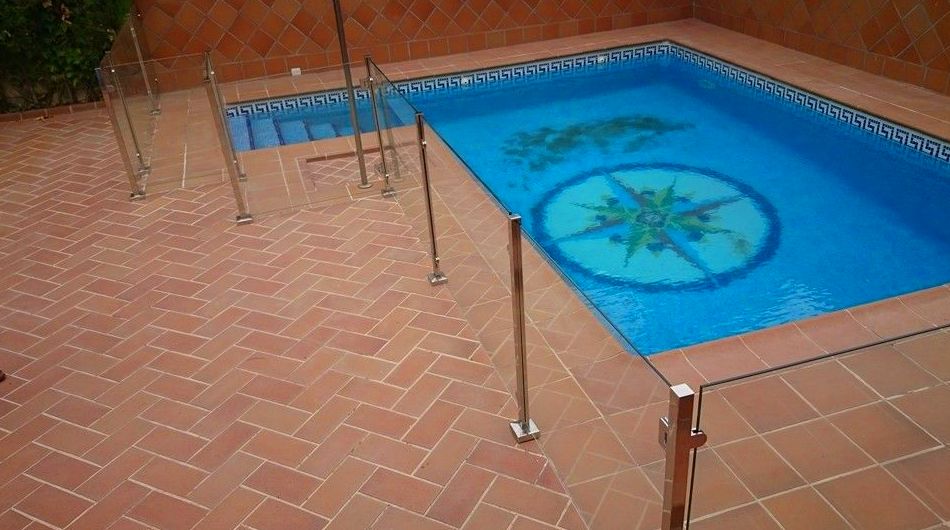 Barandilla de acero inoxidable y vidrio con puerta de acceso a piscina diseñada y fabricada a medida para vivienda particular. }}