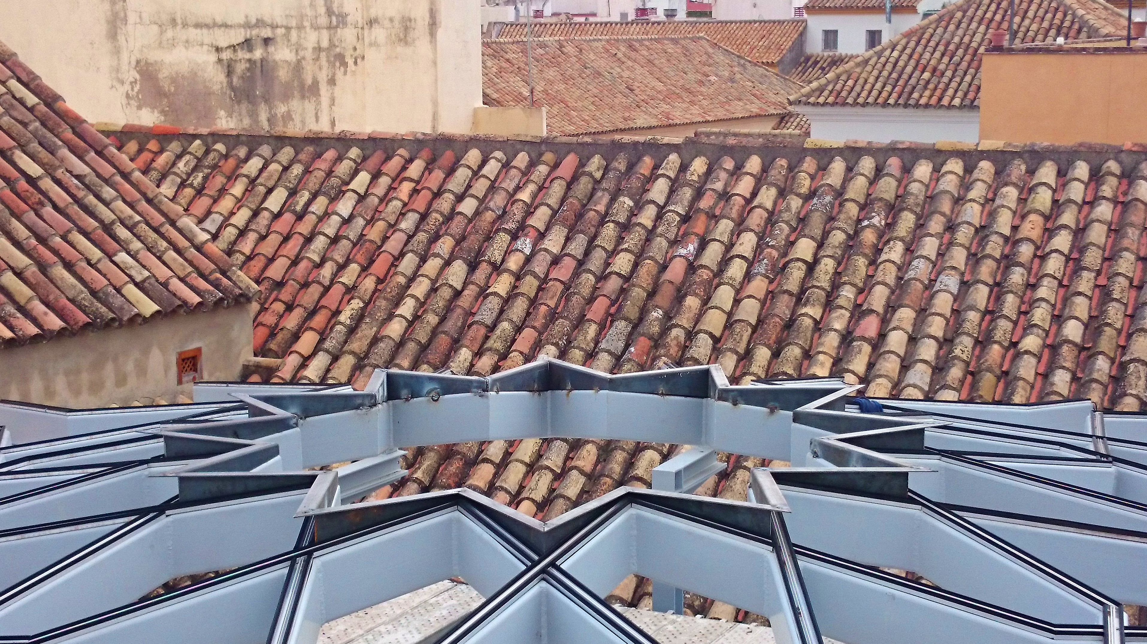 Estructura de acero negro con forma de estrella formando una base totalmente plana para alojar un vidrio con la misma forma diseñado y fabricado a medida para techo de patio andaluz de palacete Estructura de acero negro con forma de estrella formando una base totalmente plana para alojar un vidrio con la misma forma diseñado y fabricado a medida para techo de patio andaluz de palacete
