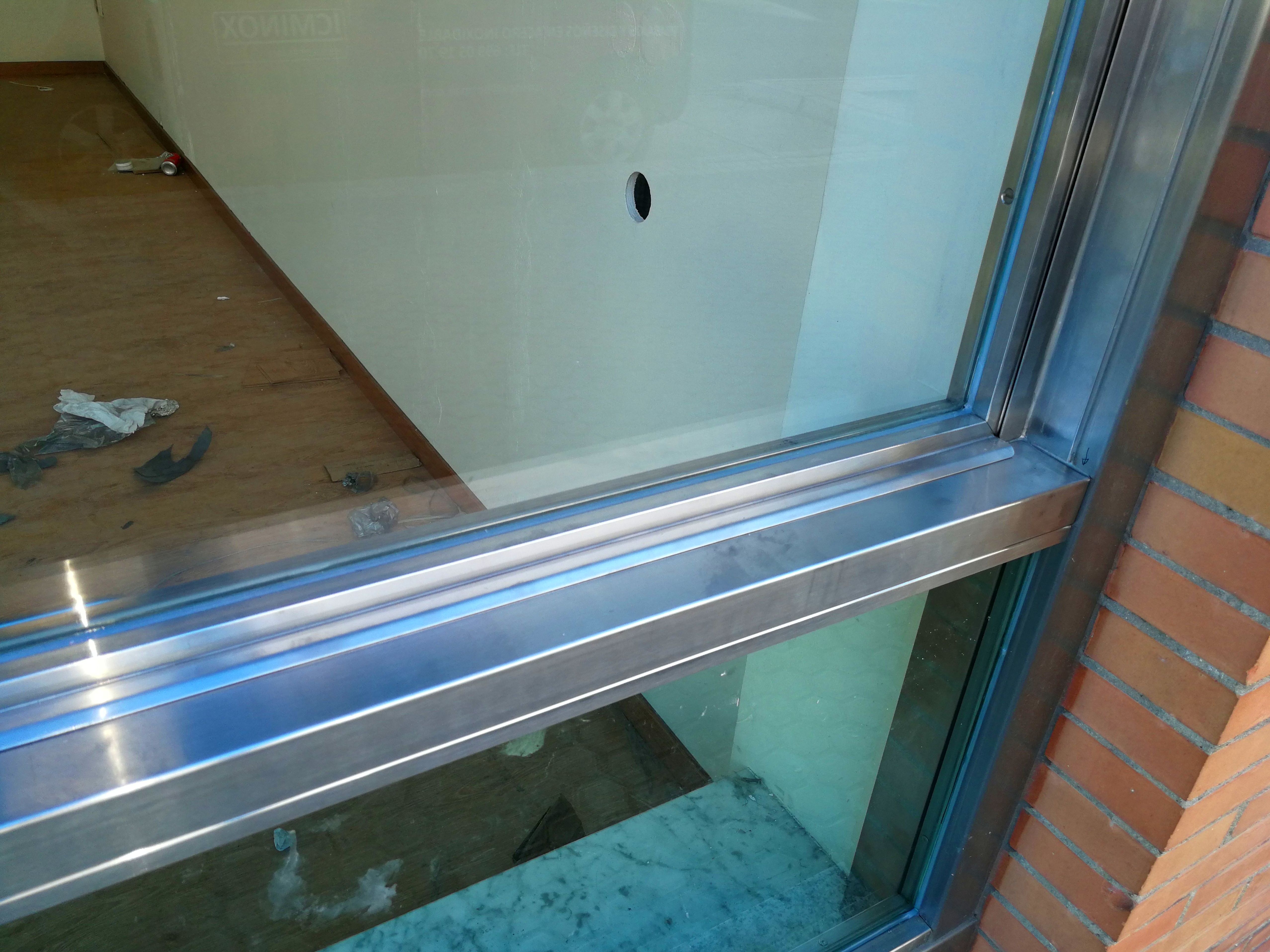 Ventana guillotina de acero inoxidable y vidrio montada para escaparate de local comercial. Ventana guillotina de acero inoxidable y vidrio montada para escaparate de local comercial.