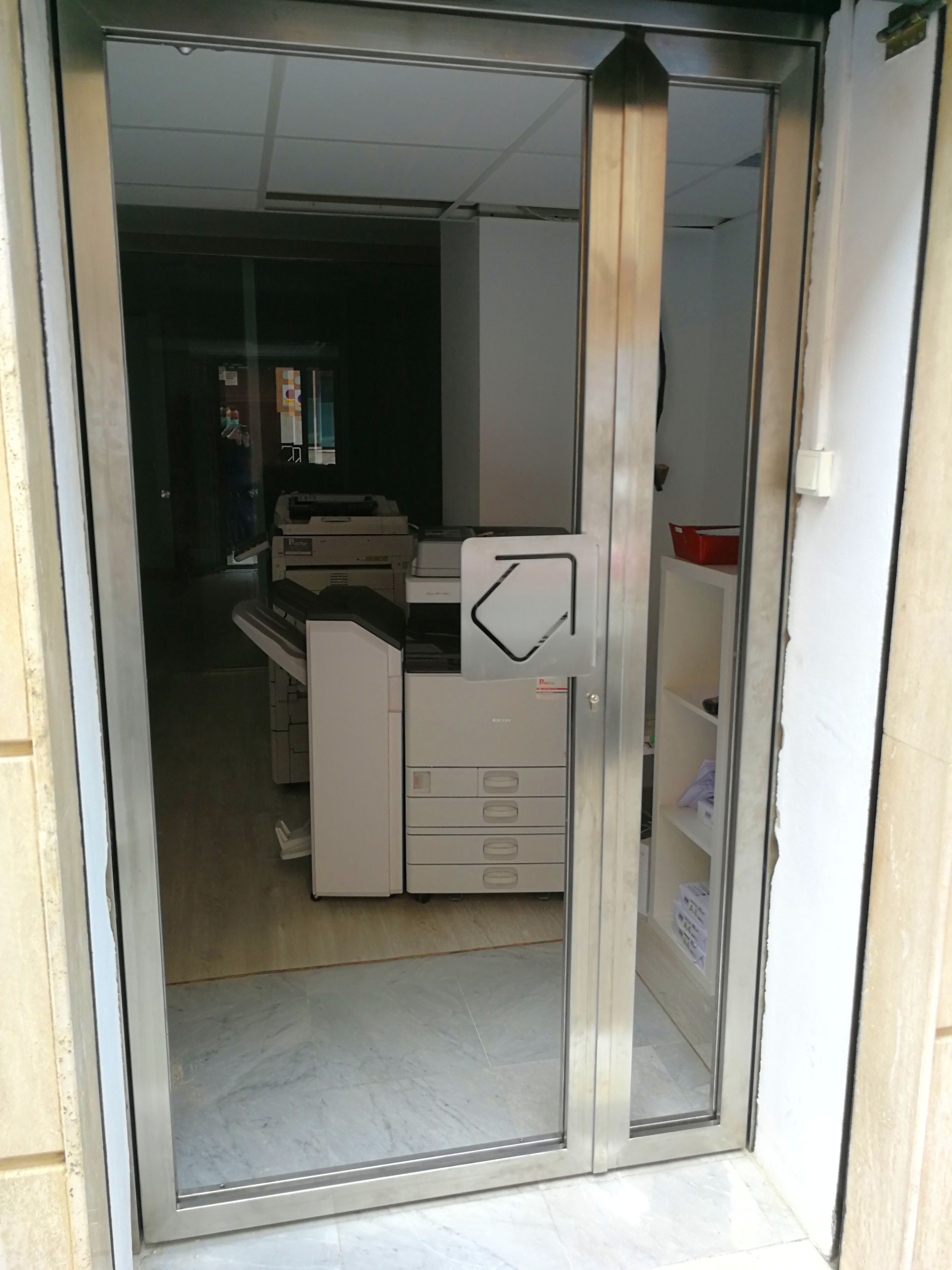 Puerta de acero inoxidable y vidrio con tirador de acero inoxidable personalizado con el logo de la empresa Puerta de acero inoxidable y vidrio con tirador de acero inoxidable personalizado con el logo de la empresa