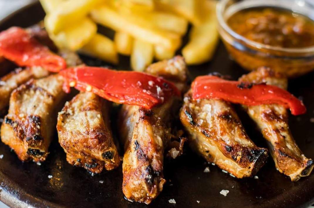 Costillas de cerdo a la parrilla con patatas fritas caseras y chimichurri Costillas de cerdo a la parrilla con patatas fritas caseras y chimichurri