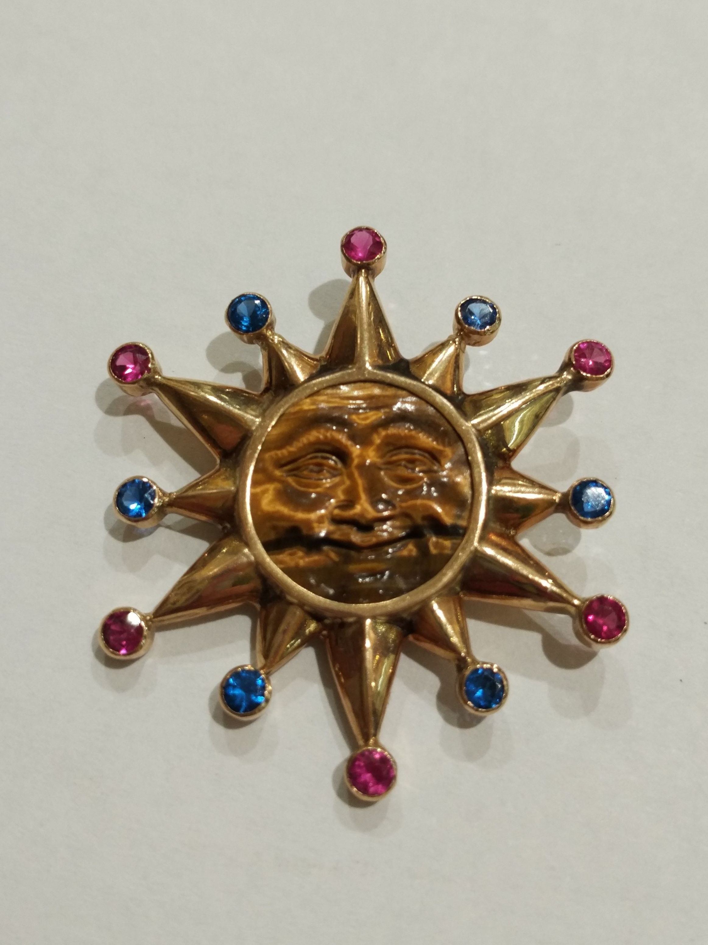 Colgante de sol en oro de 18k con ojo de tigre y vidrios. 1980.: Catálogo de Antigua Joyeros Colgante de sol en oro de 18k con ojo de tigre y vidrios. 1980.: Catálogo de Antigua Joyeros