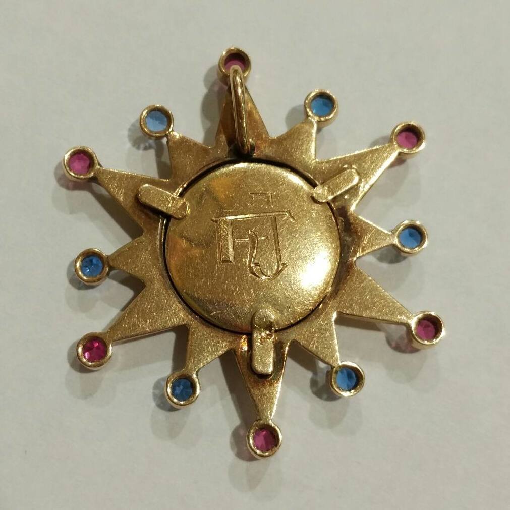 Colgante de sol en oro de 18k con ojo de tigre y vidrios. 1980.: Catálogo de Antigua Joyeros Colgante de sol en oro de 18k con ojo de tigre y vidrios. 1980.: Catálogo de Antigua Joyeros