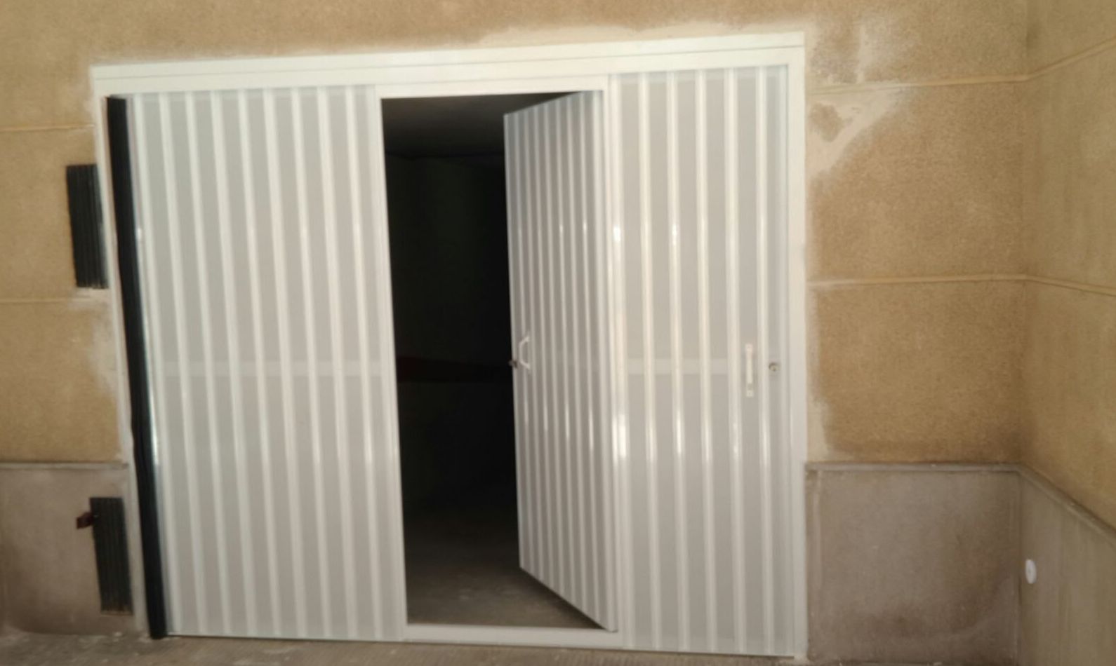 Puerta batiente lama microperforada lacada en blanco, con portón peatonal inscrito Puerta batiente lama microperforada lacada en blanco, con portón peatonal inscrito