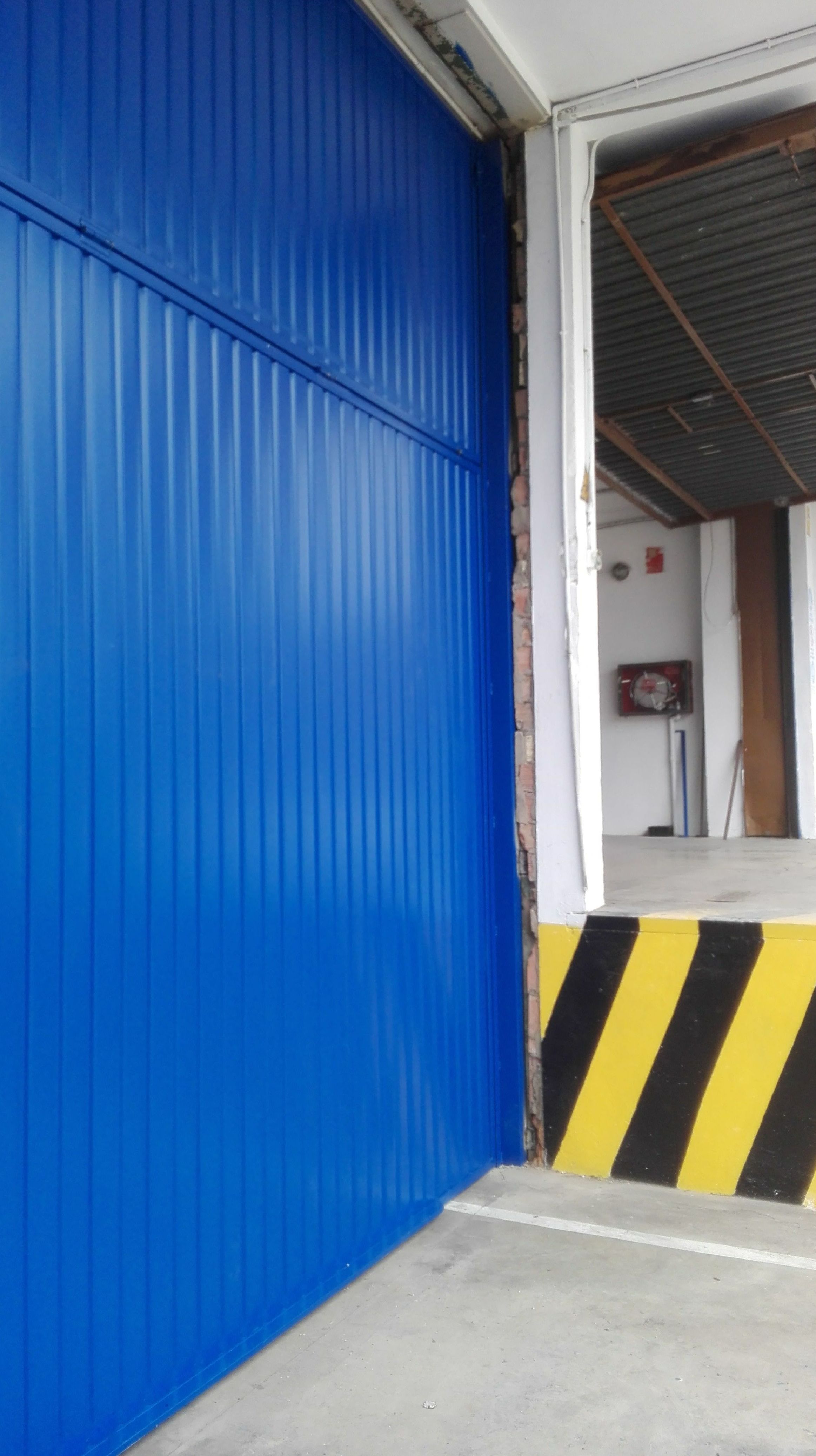 Puerta basculante de contrapesos de chapa metálica galvanizada pintura de color azul 5005 en Paterna